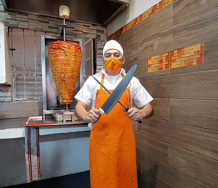 tacos-a-domicilio-en-costa-azul-trompo-carne-al-pastor-pastorero Taquero con cuchillos para preparar tacos en la sucursal de Costa Azul Los Tarascos