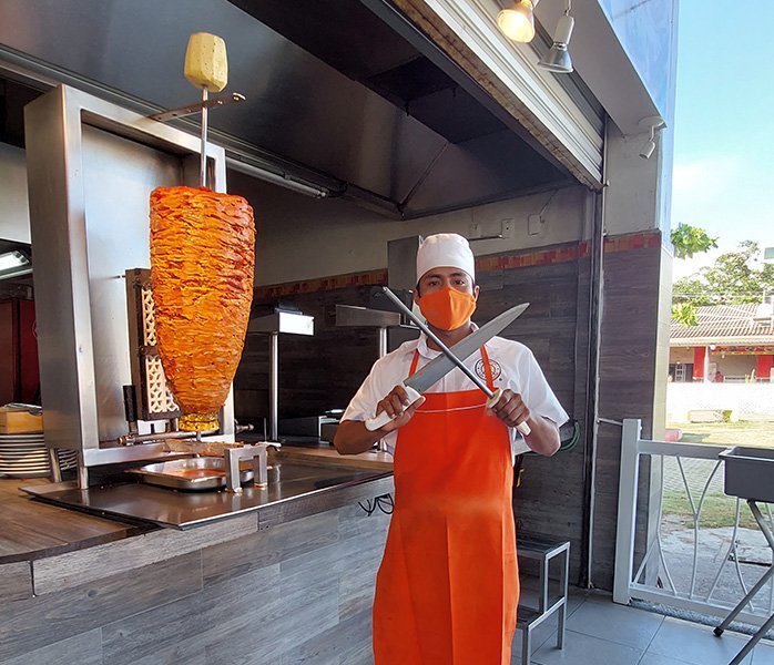 tacos-en-diamante-trompo-carne-al-pastor hombre con cuchillos para cocinar tacos al pastor en Diamante Acapulco
