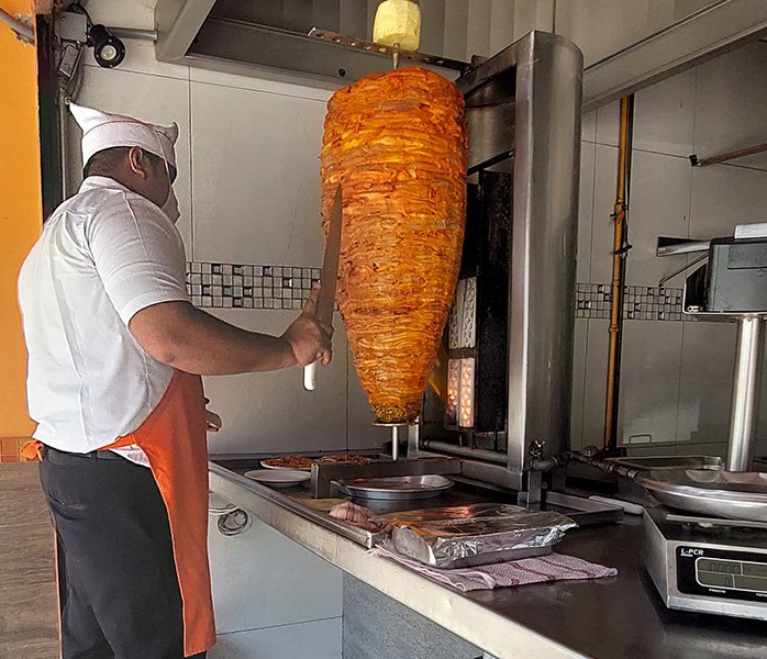 tacos-en-forum-acapulco-trompo taquero preparando tacos de carne al pastor en sucursal forum Acapulco