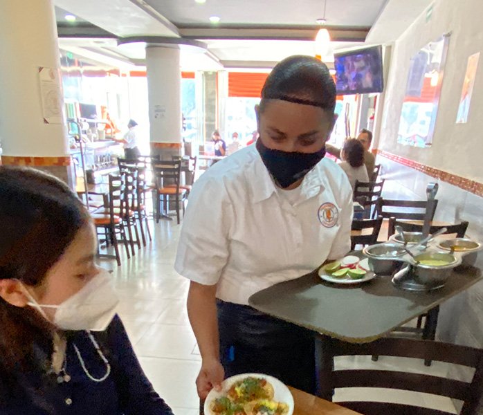 tacos-en-la-24-sur-colaboradora-sirviendo-en-mesa servicio de tacos en la 24 sur a la mesa de los clientes de Los Tarascos